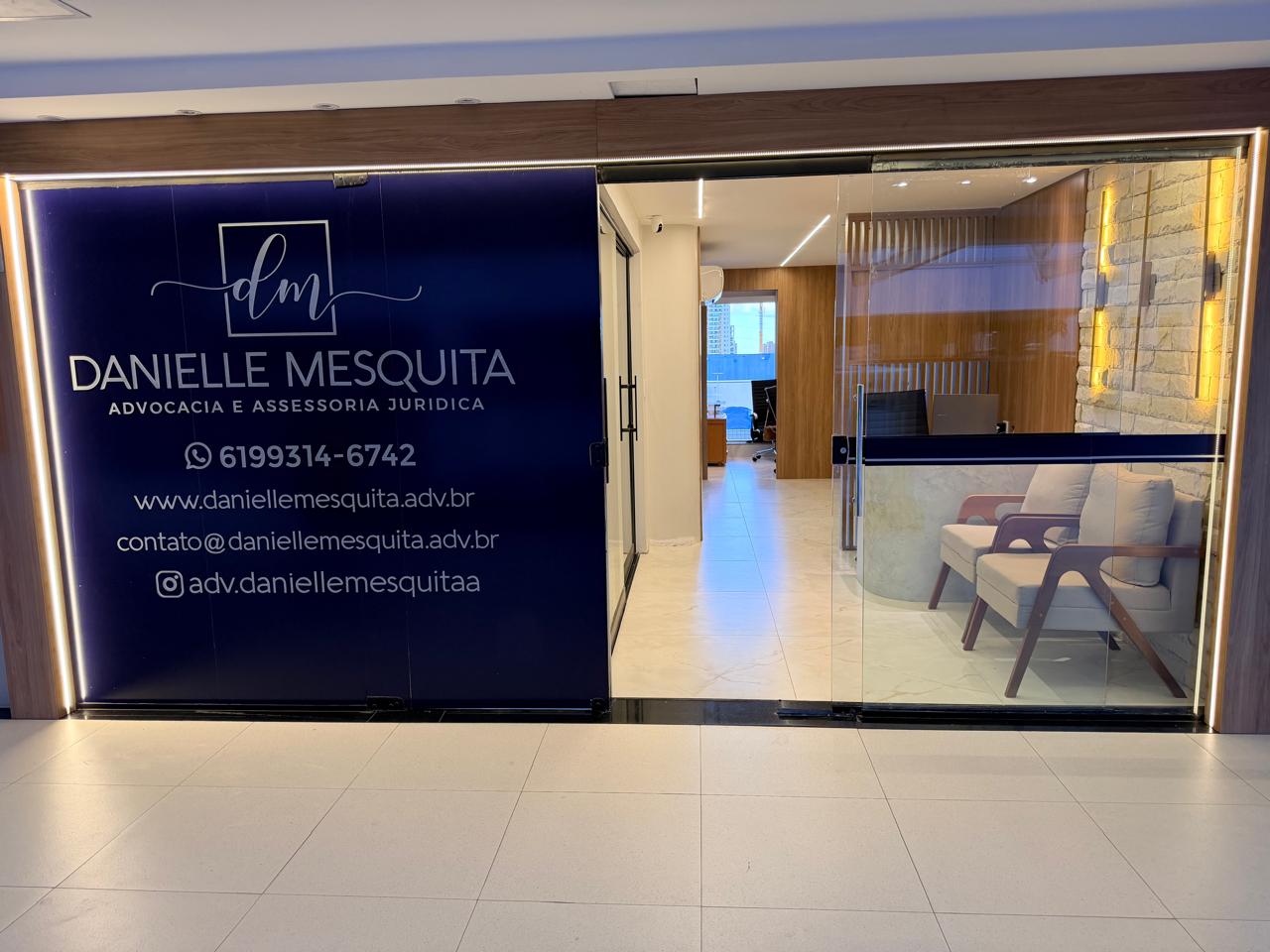 Fachada do escritório Danielle Mesquita Advocacia com painel da marca e entrada envidraçada mostrando a recepção interna.